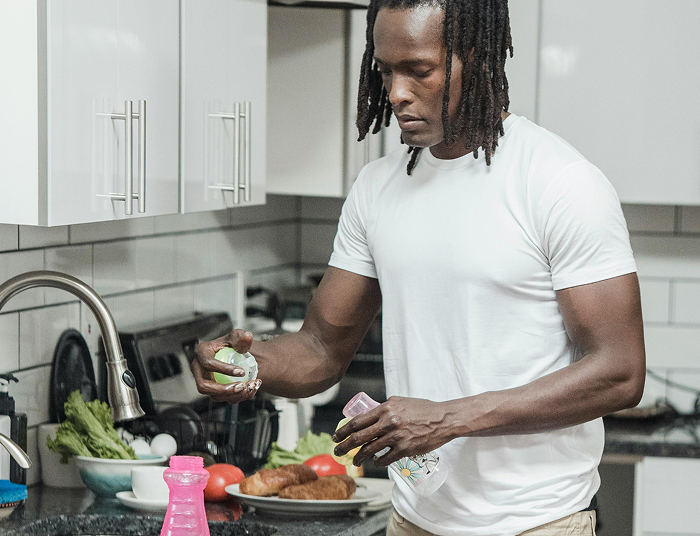 Man in a kitchen preparing food, using spices to entertain himself with creative cooking.