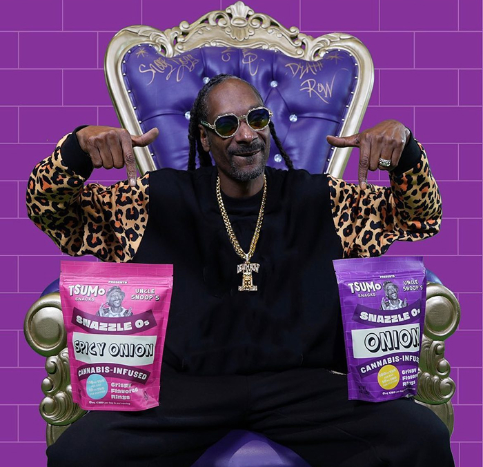 Snoop Dogg wearing a leopard-print jacket sits on a throne, showcasing Snazzle Os cannabis snacks.