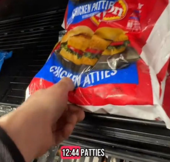 Close-up of a hand holding a bag of chicken patties, highlighting grocery prices in the US.