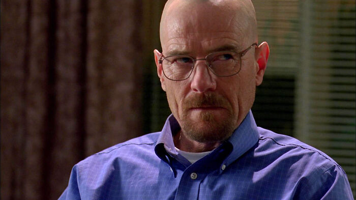 Bald man in glasses and a blue shirt with a stern expression, exemplifying his iconic role.