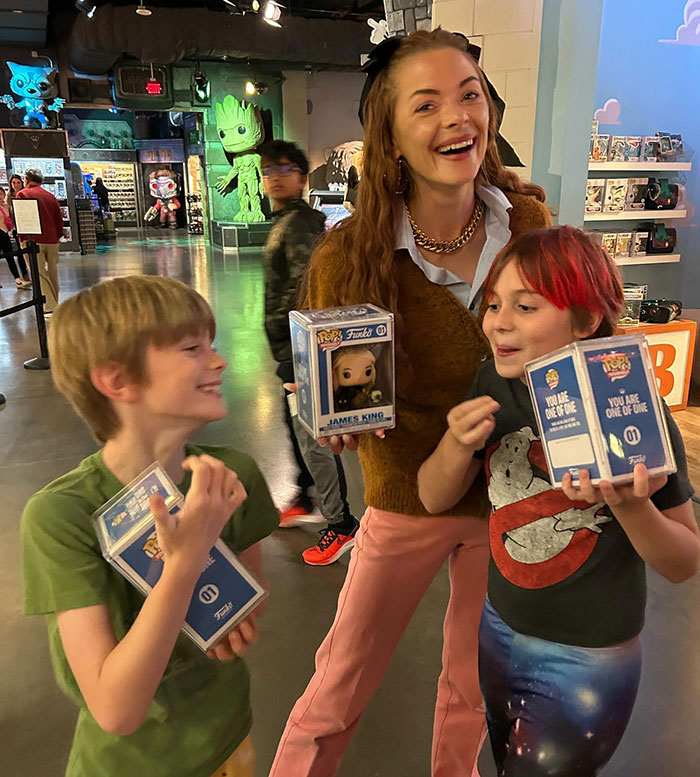 Smiling woman with two children holding collectible boxes, related to Taylor Swift's friend Jaime King. Smiling woman with two children holding collectible boxes, related to Taylor Swift's friend Jaime King.