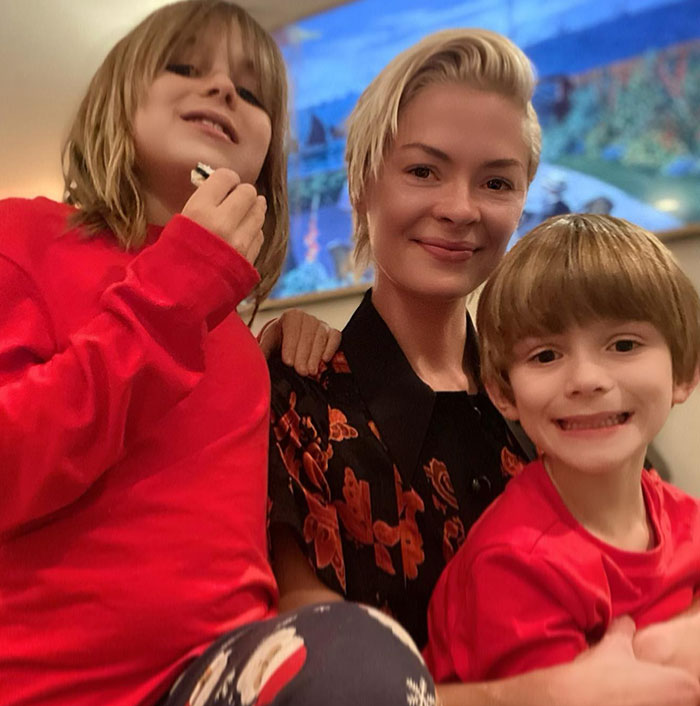 Taylor Swift&rsquo;s godson with two children, smiling indoors, capturing a cheerful moment together.