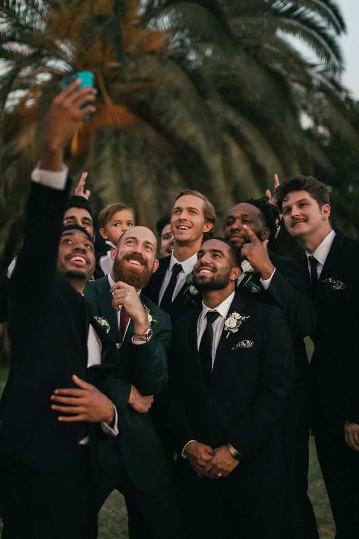 Group of groomsmen taking a selfie at a wedding, showcasing potential red flag moments.