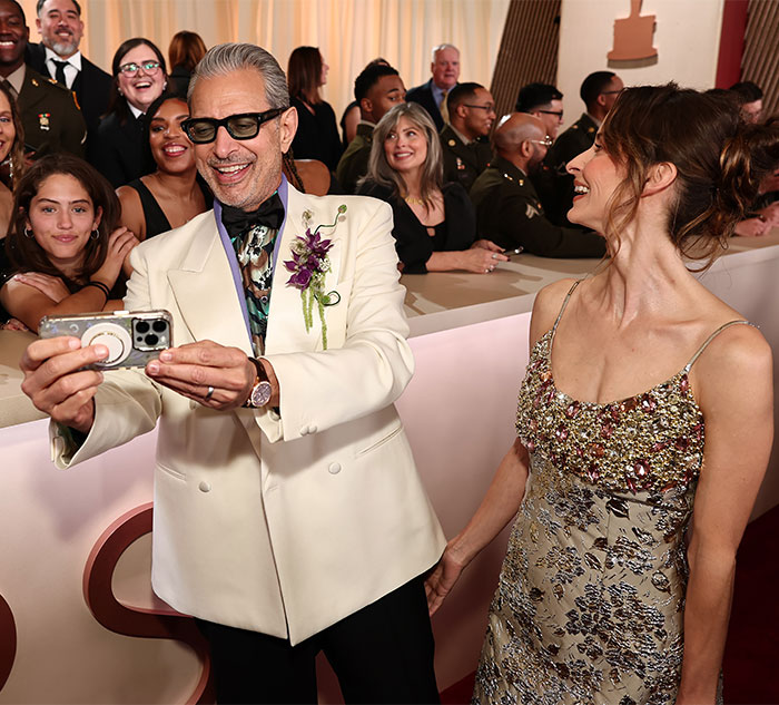 Celebrities taking selfies and laughing in elegant attire at Oscars 2025, capturing a behind-the-scenes moment.