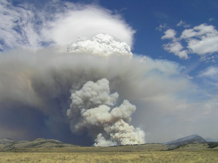 Smoke plume from a large wildfire, illustrating dark history facts about natural disasters.