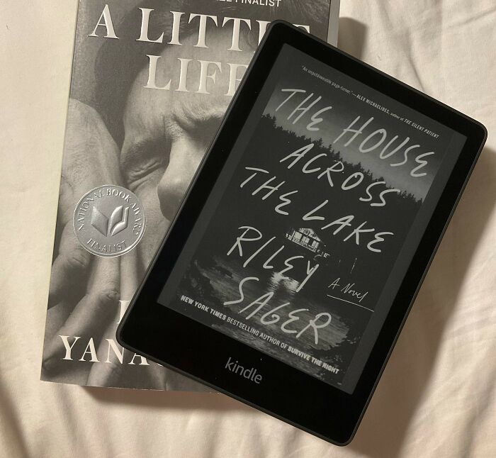 Kindle displaying "The House Across the Lake" next to "A Little Life" book on a bed.