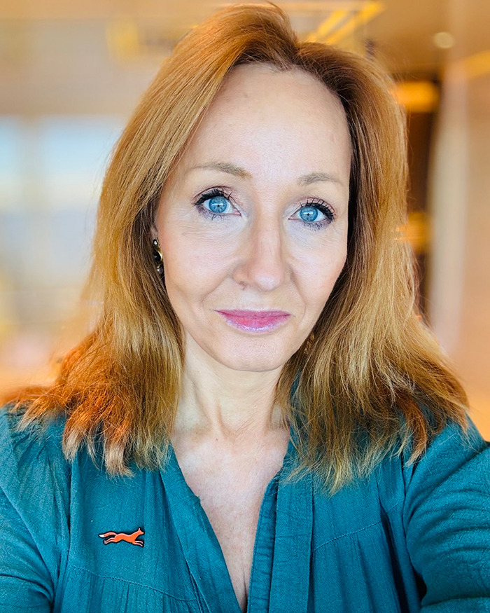 A person with long hair and blue eyes in a room, wearing a green shirt, related to Harry Potter controversy.