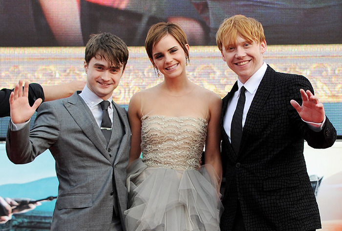 Harry Potter stars smiling and waving at a movie premiere event.