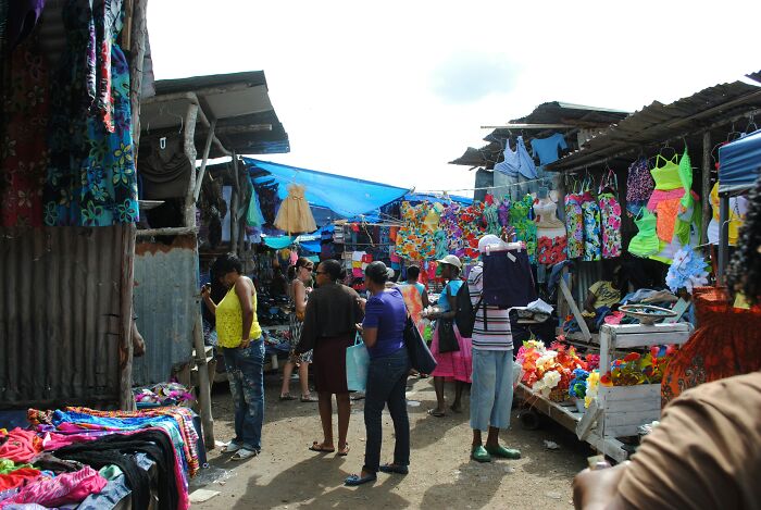 People browsing vibrant clothing at a local market, a touristy place not worth the hype per seasoned travelers.