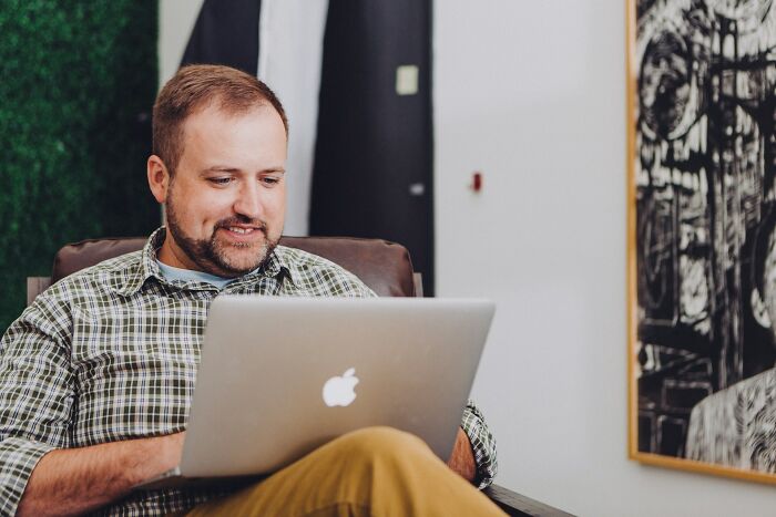 Man in plaid shirt using a laptop in a cozy setting, focusing on sudden dizziness awareness.