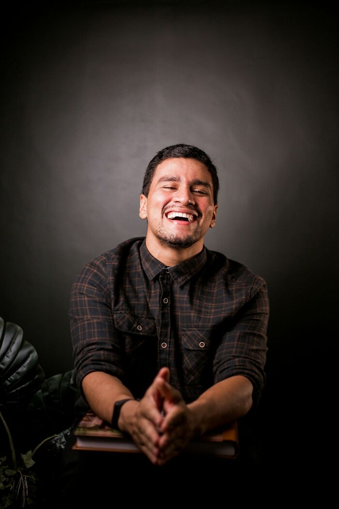 Man smiling in a relaxed pose, wearing a plaid shirt.