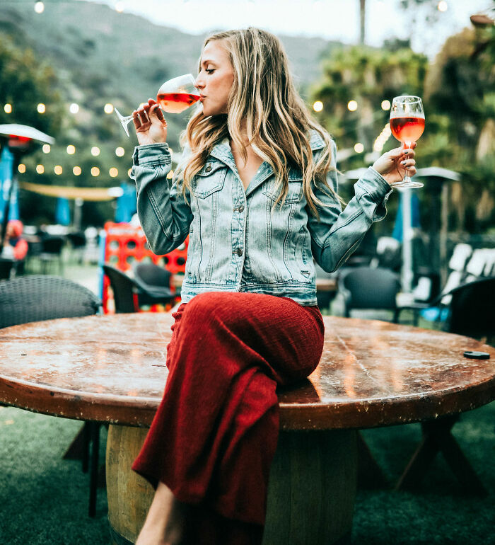 Woman in a denim jacket enjoying wine outdoors, exemplifying therapist judgment moments.