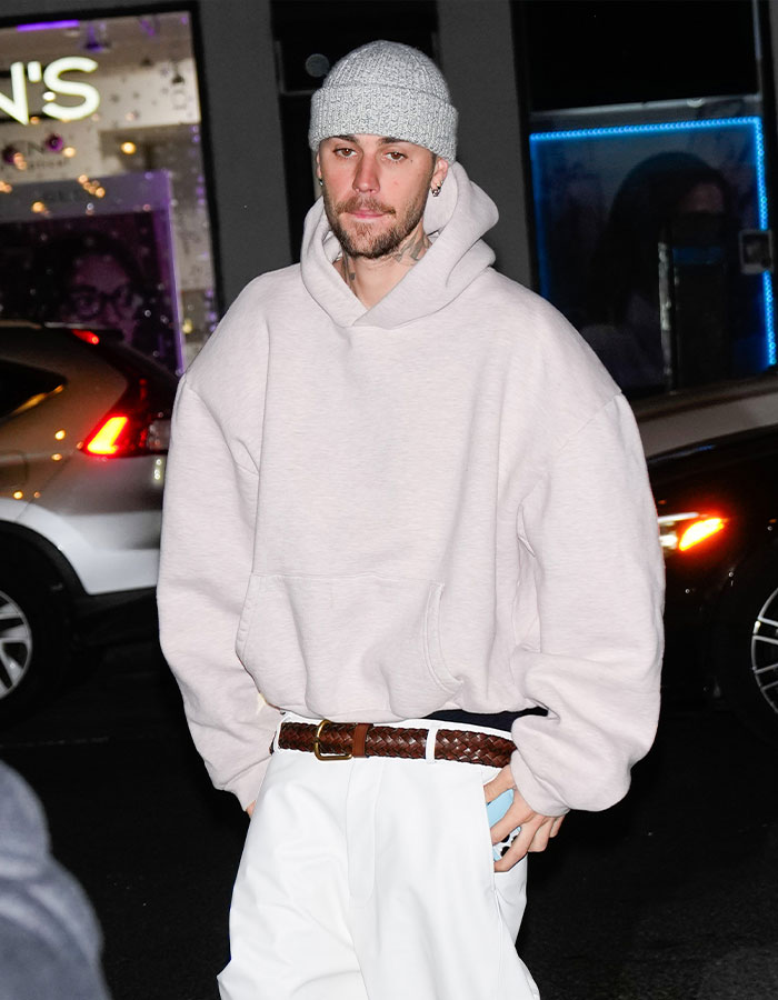 A person wearing a gray beanie and oversized hoodie, associated with impostor syndrome topic.