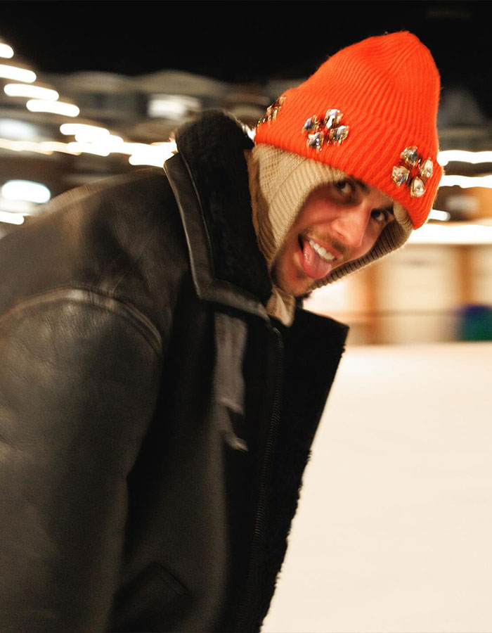 Person in a bright orange beanie and black jacket smiling, embodying themes of Impostor Syndrome.