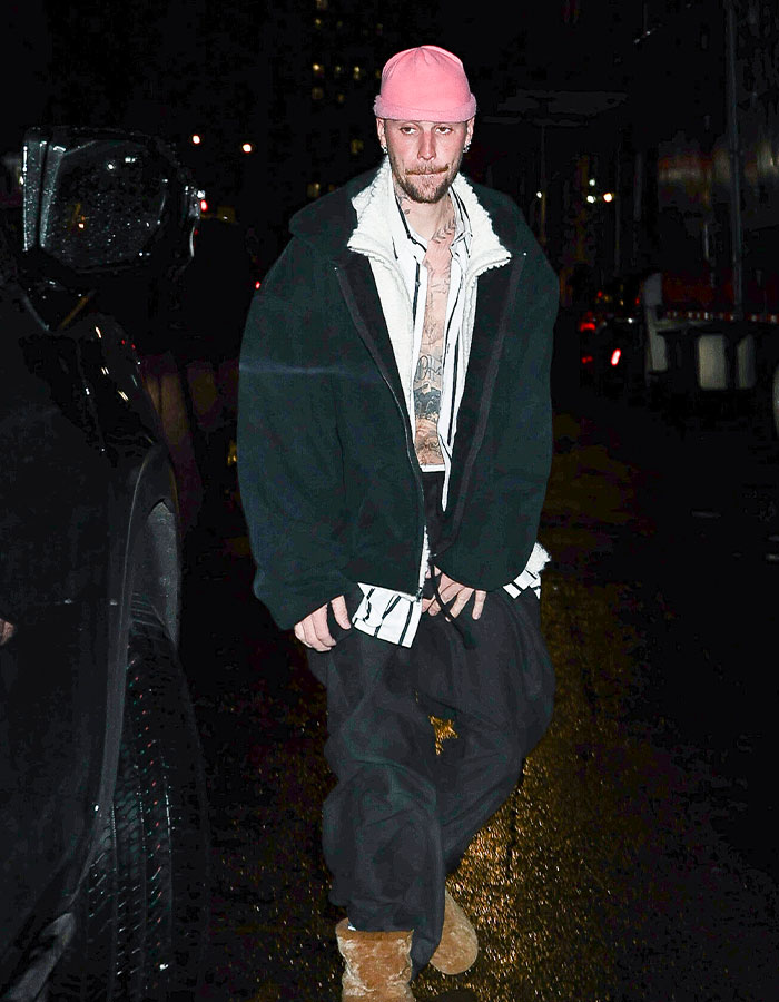 Person wearing a pink cap and black jacket walking at night, touching on impostor syndrome themes in recent news.