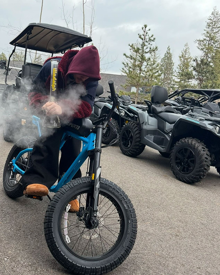 Justin Bieber smoking on a blue bike, surrounded by off-road vehicles.