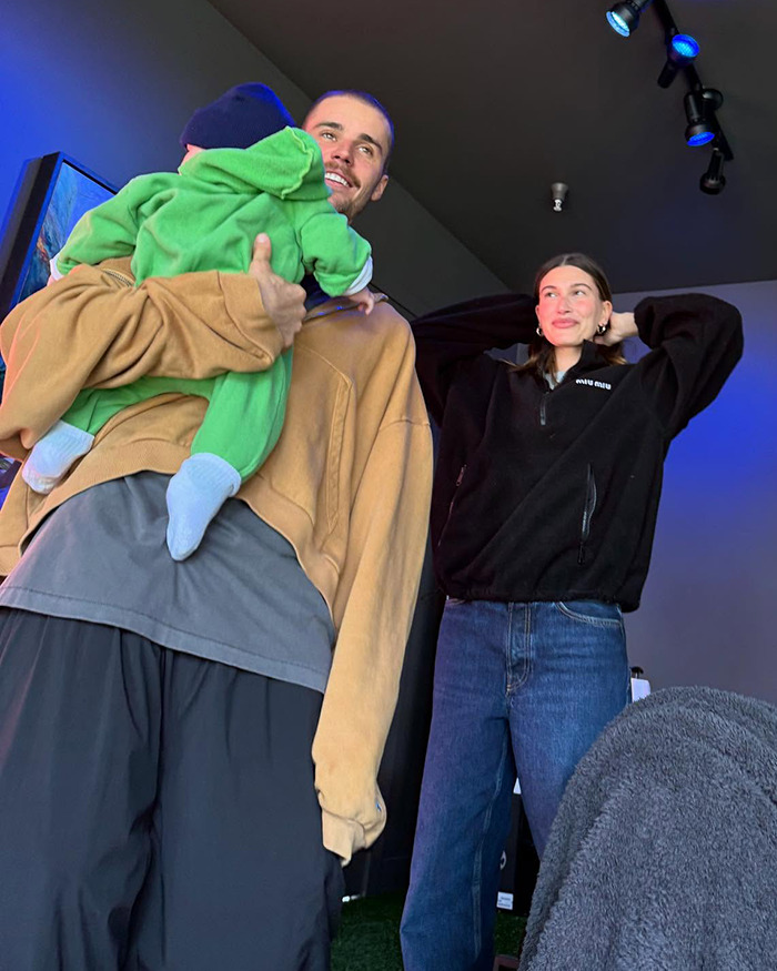 Justin Bieber holding son Jack in a casual setting, smiling, with Hailey Bieber standing nearby.