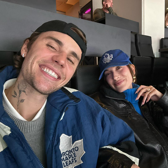 Justin Bieber and Hailey smiling at Disneyland, with Bieber wearing a Toronto Maple Leafs jacket.