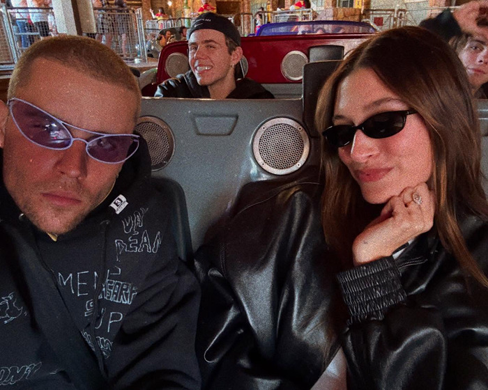 A couple enjoying Disneyland, wearing stylish sunglasses, seated on an amusement ride.