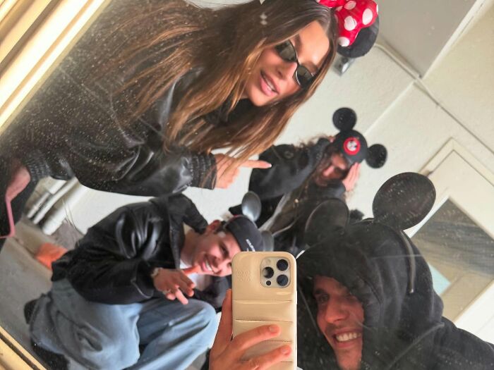 People in playful Mickey Mouse hats take a group selfie, focusing on Bieber's health as a keyword topic.