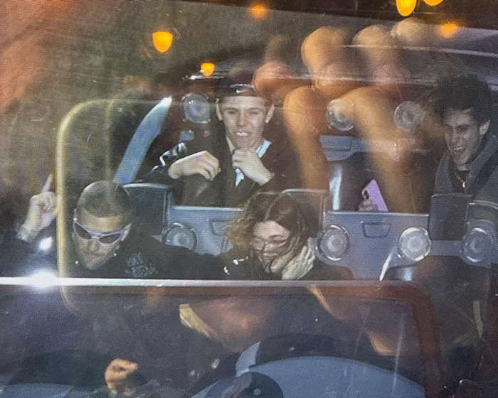 Justin Bieber and Hailey enjoying a ride at Disneyland, smiling with friends, in a relaxed setting.