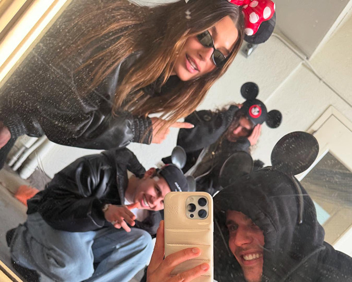 Justin Bieber and Hailey at Disneyland in fun Mickey Mouse attire, capturing the moment with friends.