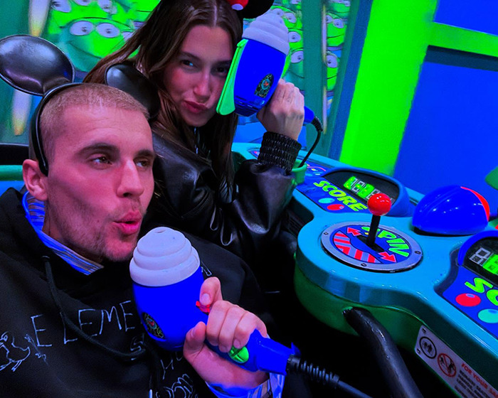 Justin Bieber and Hailey enjoying a ride at Disneyland, wearing Mickey Mouse ears and holding toy blasters.