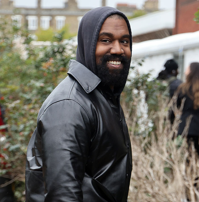 A man in a black leather jacket and hoodie smiling outdoors, linked to controversy with Beyonc&eacute; and Jay-Z.