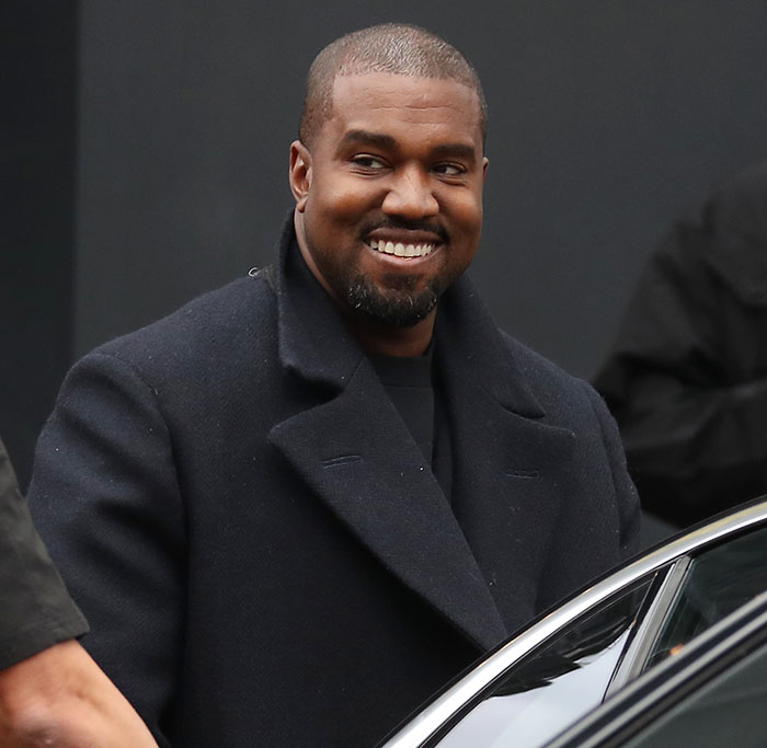 Man in black coat smiling near car, associated with human trafficking accusation news.