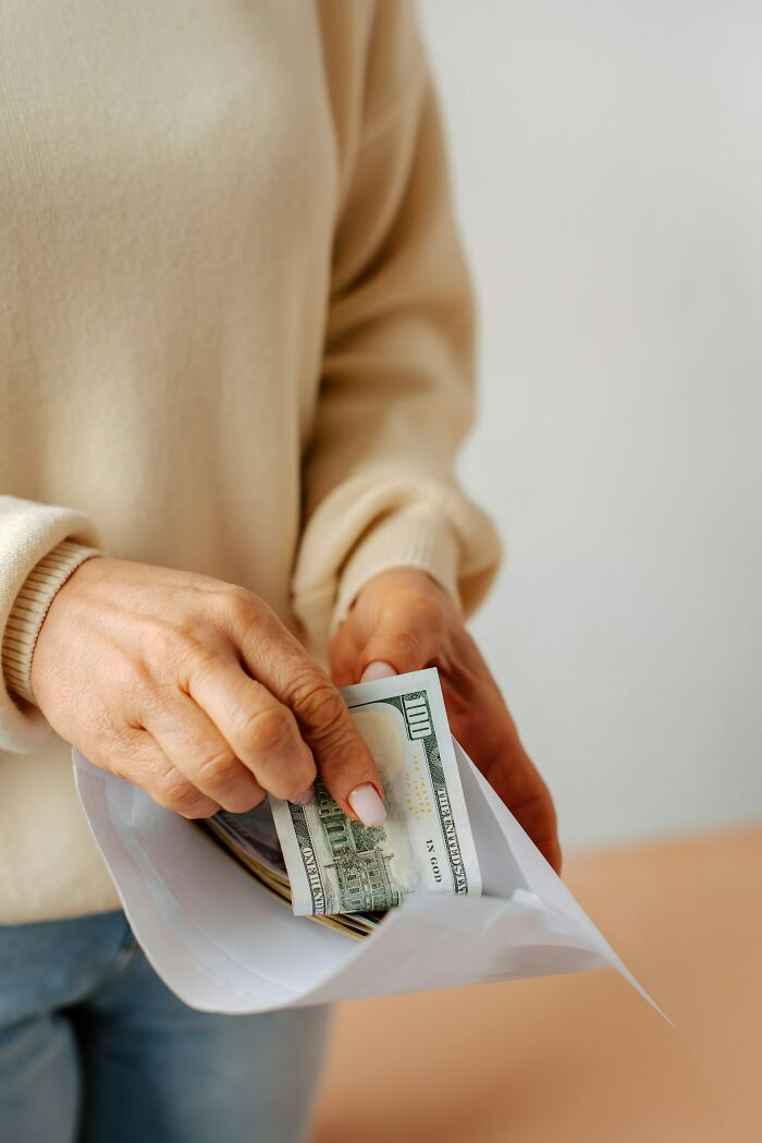 Person holding cash in an envelope, suggesting a wedding red flag moment.