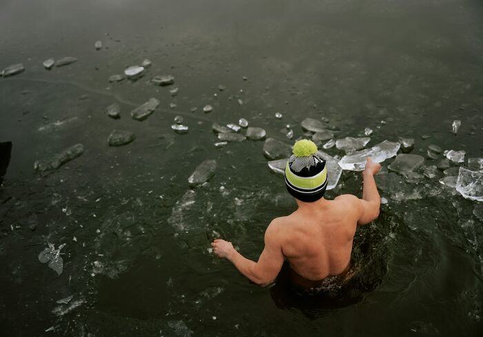 Man in cold water surrounded by ice, highlighting sudden dizziness risks in extreme conditions.