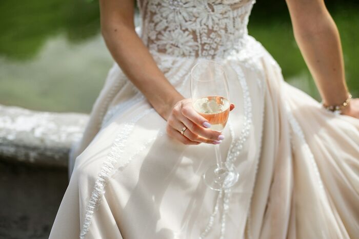 Bride in elegant gown holding a champagne glass, highlighting wedding red flags theme.