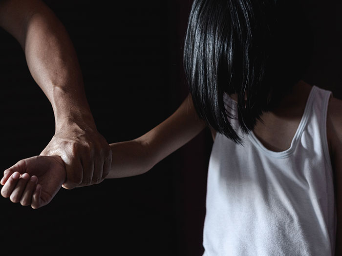 Kansas trooper rescues kidnapped 6-year-old girl held by the arm in a dimly lit setting. Kansas trooper rescues kidnapped 6-year-old girl held by the arm in a dimly lit setting.