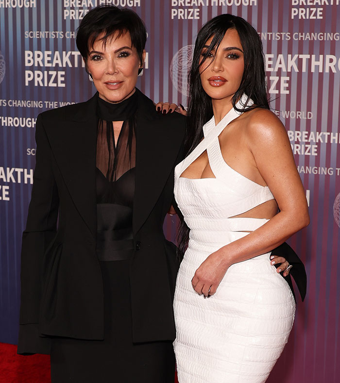 Kim Kardashian at an event in a white dress, posing for photos.