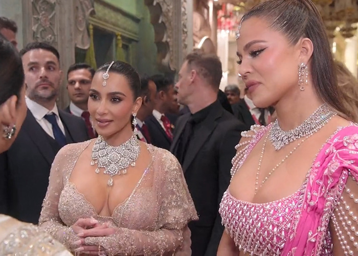 Two women in elegant dresses at a formal event, surrounded by people, conversation and luxury ambiance.