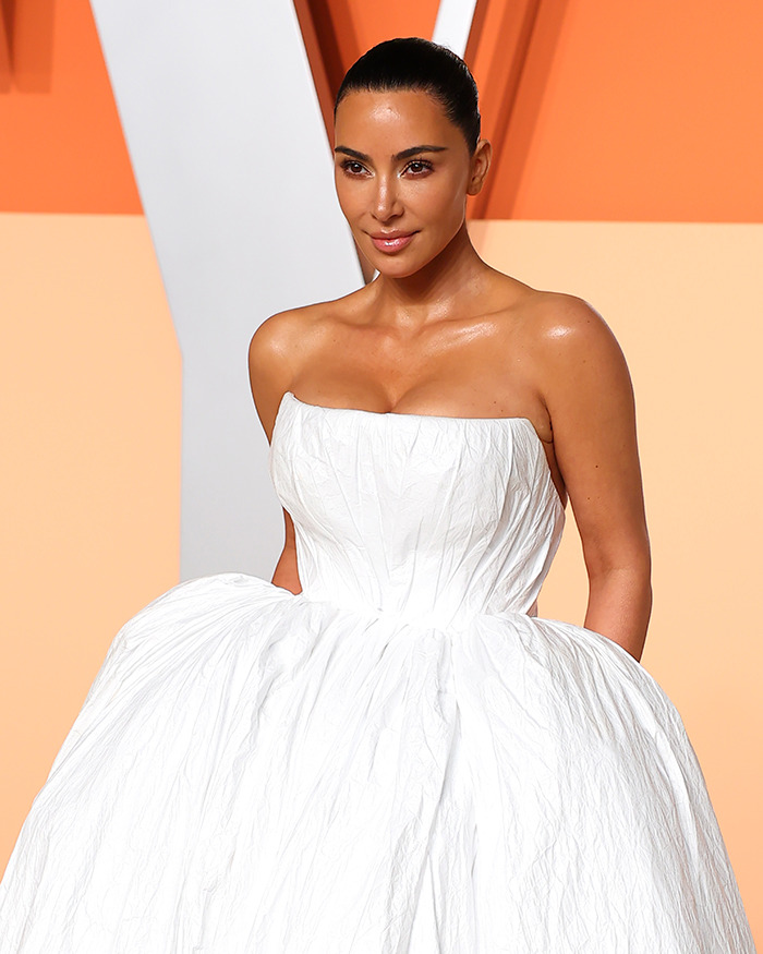 Kim Kardashian in a strapless white dress, resembling toilet paper, with a tan, attending an Oscars after party.