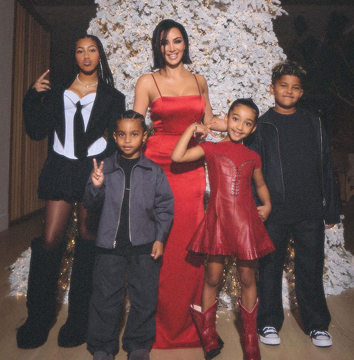 Kim Kardashian poses with her children in front of a festive tree, amid allegations from Kanye.