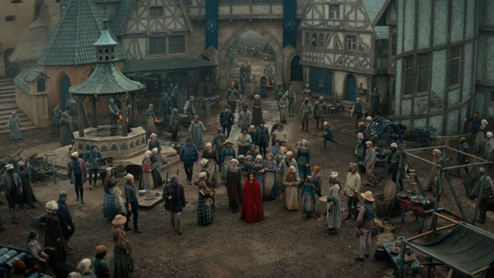 A bustling medieval village scene from the new Snow White remake depicts townspeople gathered around a central square.