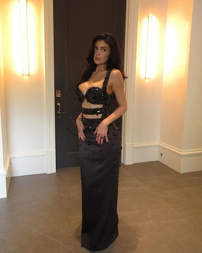 Kylie Jenner in a black embellished dress posing indoors.