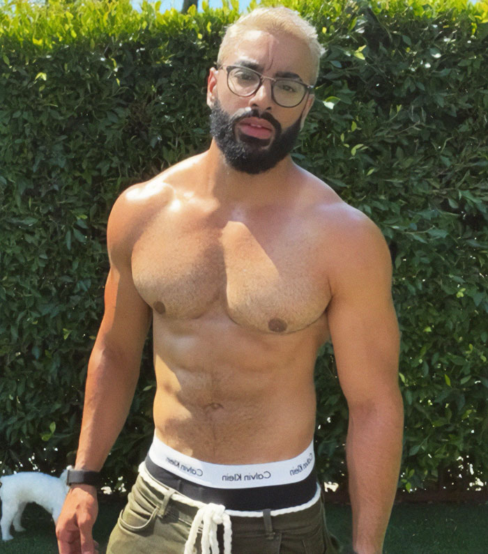 Transgender actor posing outdoors, wearing glasses and Calvin Klein boxers.