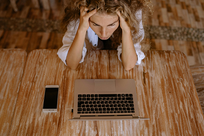 Woman stressed over laptop, contemplating decision about husband's affair child and money.