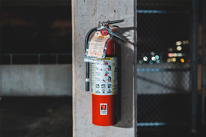 A fire extinguisher mounted on a concrete wall, part of life-saving emergency equipment essentials.