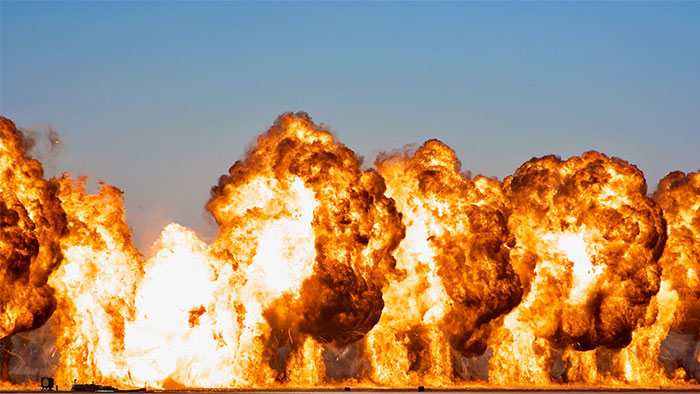 Massive explosion with large fireballs against a clear sky, emphasizing life-saving emergency awareness.