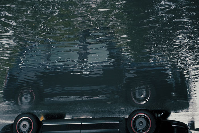 Reflection of a car on a wet road surface, illustrating a life-saving tip for driving in rainy conditions.