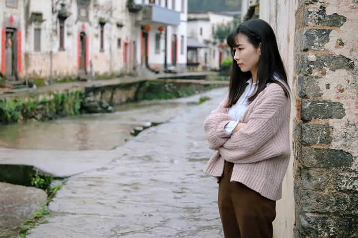 Bridesmaid pensive by a canal, contemplating her decision to leave a wedding.