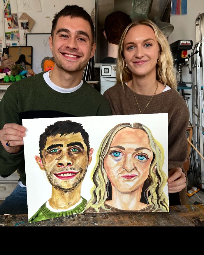 British artist's expressive portrait held by two smiling individuals in a creative studio.