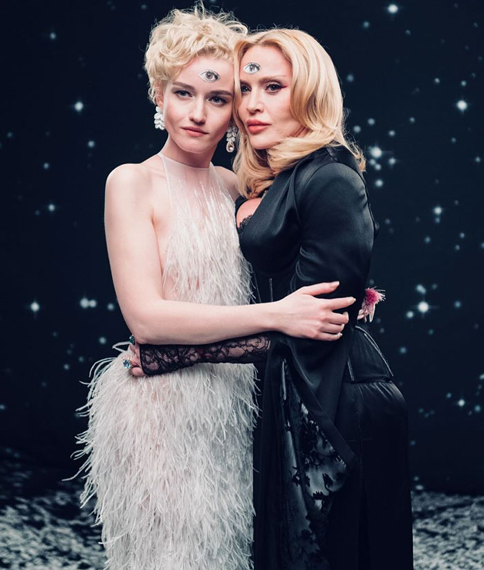 Two people in elegant outfits embracing, with one displaying a smooth face, against a starry background.