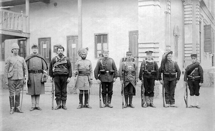Soldiers from different nations in uniform, lined up in front of a building, related to terrifying backstories.