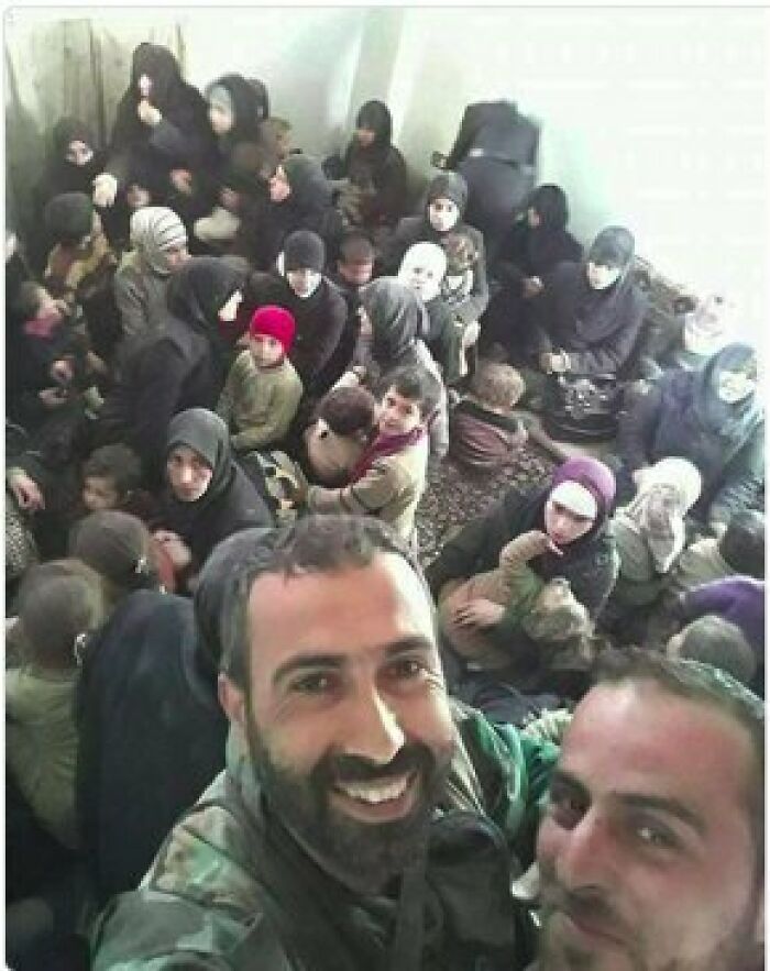 Grupo de personas en una habitación, con dos hombres sonriendo al frente.