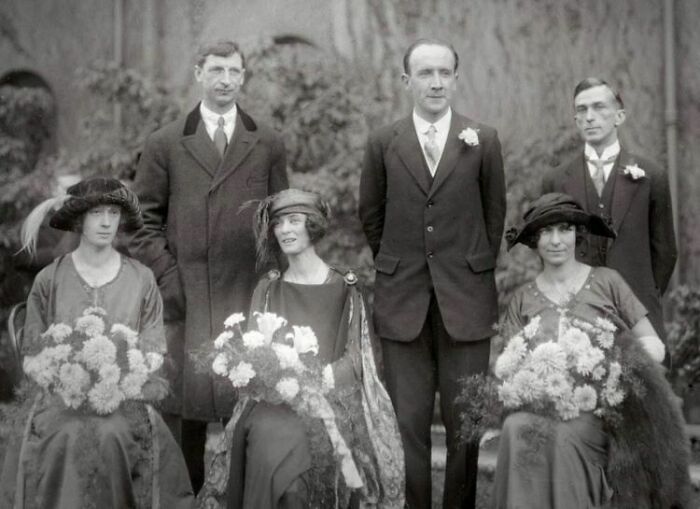 Vintage group portrait of well-dressed people with flowers, linked to a seemingly normal photo with a terrifying backstory.